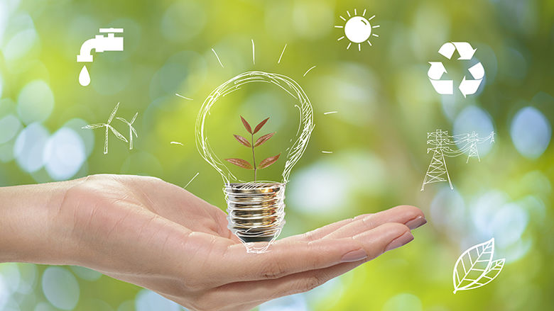 A hand holding a drawing of a light bulb representing renewable energy