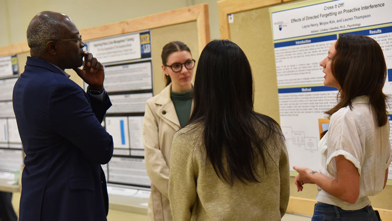 Penn State Altoona Chancellor Ron Darbeau listens to an explanation of research conducted by students Layna Henry, Minjoo Kim and Lauren Thompson.