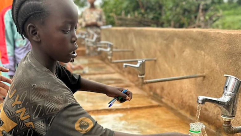 A child fills up a water bottle with clean water thanks the World Vision program
