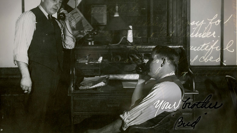 A black-and-white photo from September 9, 1942, shows two men in an office, each on the phone. The man on the left stands with a cigarette, while the man on the right is seated. The background features a cluttered desk. The image includes handwritten text and is signed Your brother, Bud.
