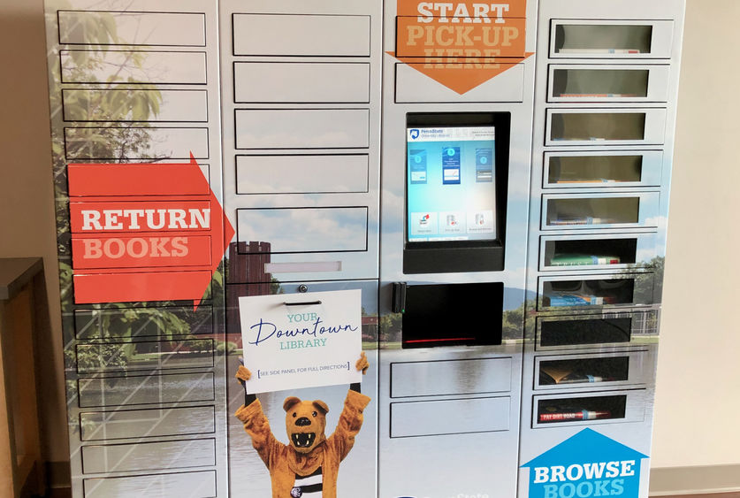 tall metal locker system with central touchscreen and dozens of small narrow doors, some with windows to see book covers