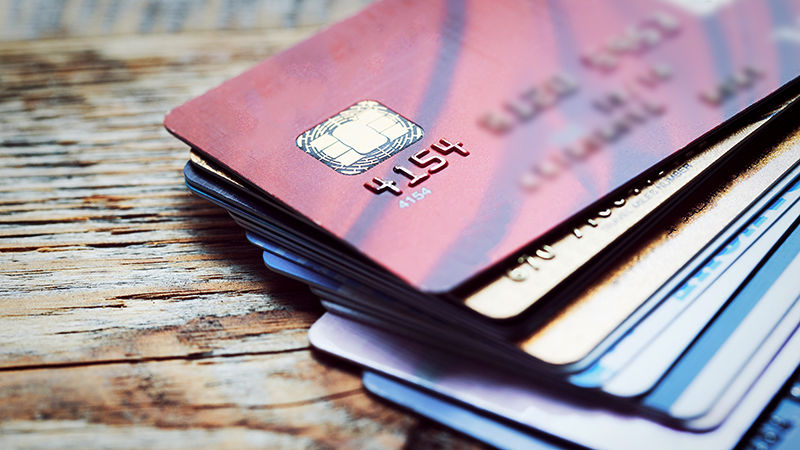 A stack of credit cards on a wooden surface