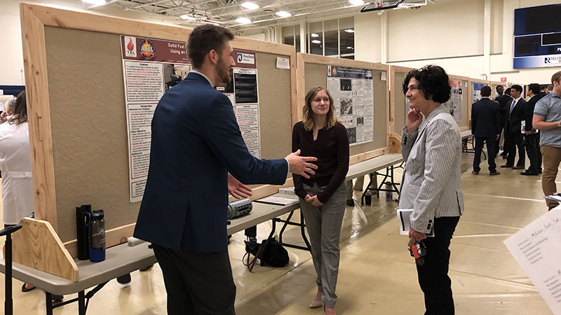 A student presents to Chancellor and Dean Lori J. Bechtel-Wherry