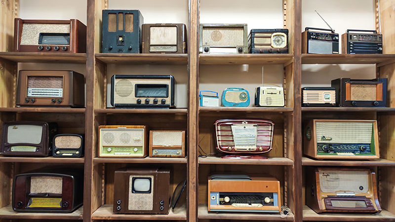 A wooden shelf housing old-fashioned radios