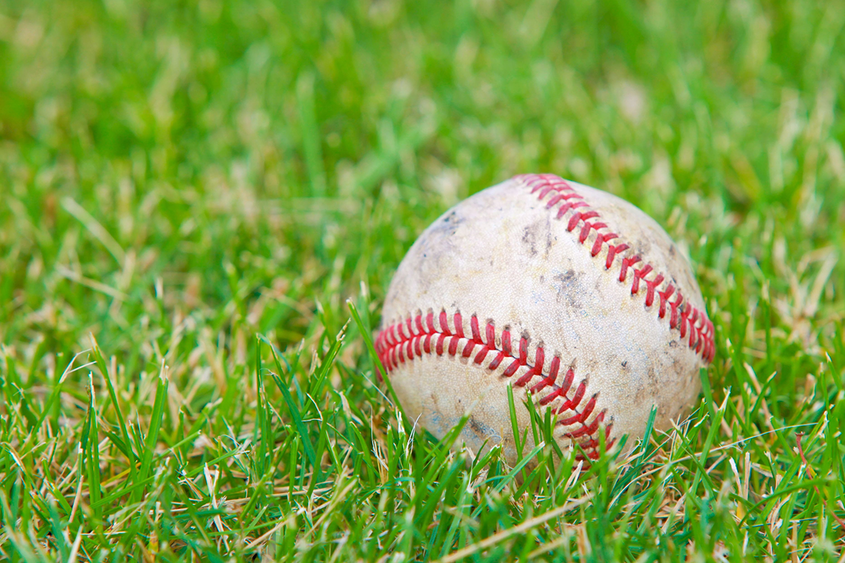 A baseball sitting in a field of grass