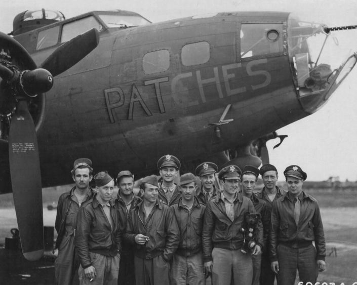 WWII flight crew stands in front of their plane in England 