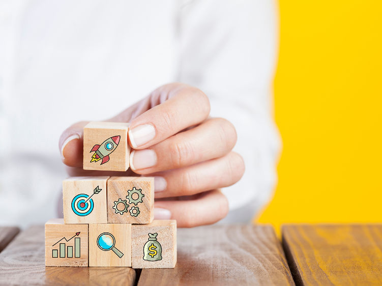 A stack of building blocks decorated with icons representing a startup