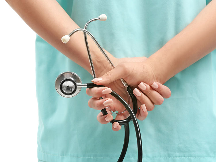 a close-up of a nurse holding a stethoscope behind her back