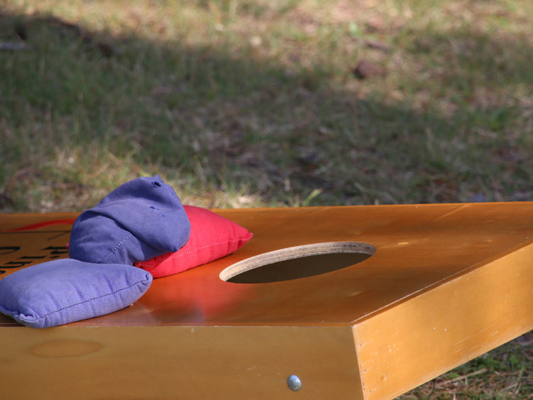 A cornhole board with several beanbags