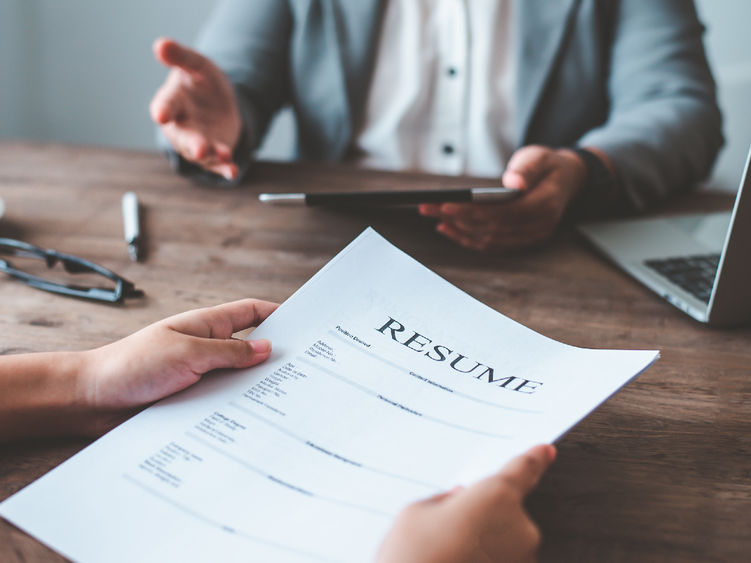 Photo of someone being interviewed while the interviewer looks at a resume