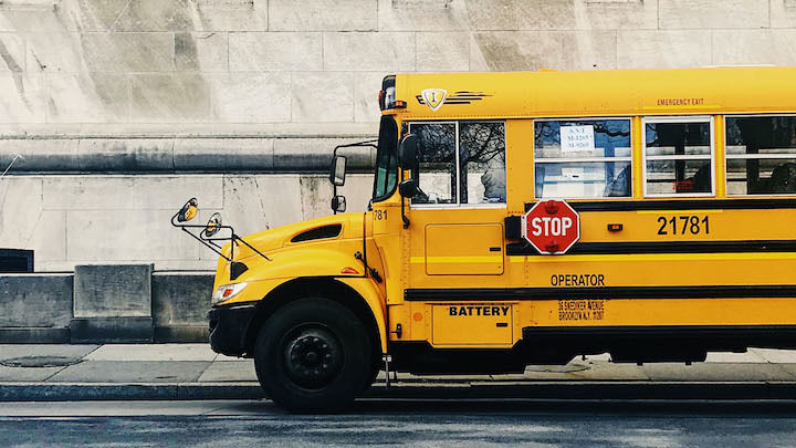 Yellow school bus outside of a school.