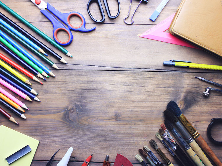 Arts and crafts materials displayed on a table including paintbrushes, colored pencils, scissors, and more