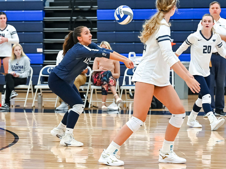 Penn State Altoona volleyball player Anna Batrus prepares to dig during a volleyball game, surrounded by teammates on the court.