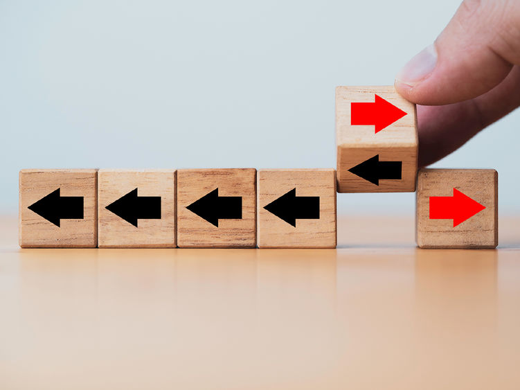 a series of small wooden blocks with arrows on them and a hand shifting the arrows from left to right