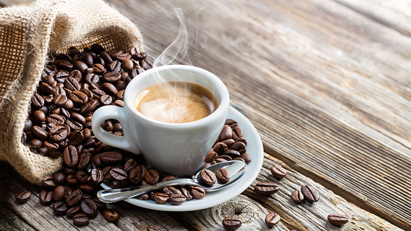 Coffee cup surrounded by coffee beans