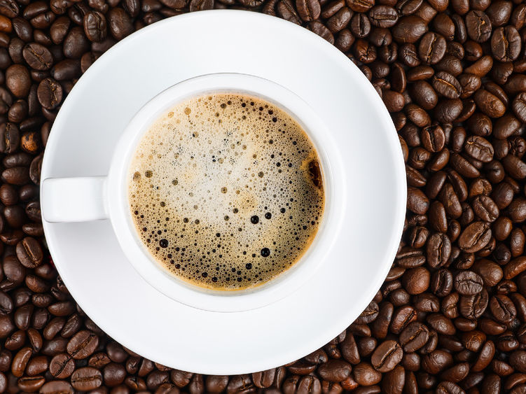 A cup of coffee sitting among coffee beans