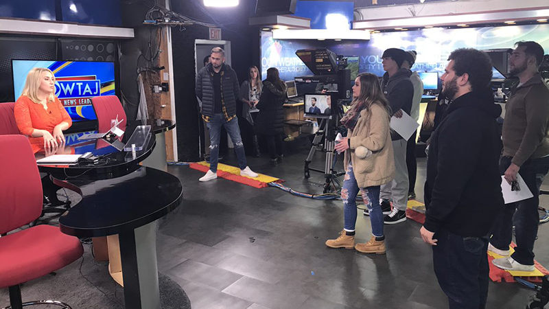 Students and studio staff look on at a live broadcast at the WTAJ news studio