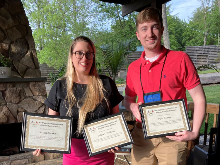 Penn State Altoona Student Tyler Frye accepting the first-place award on behalf of his peers, Rachel Kosaka and Alicia Williams, from NEACJS Student Paper Committee Chair, Dr. Danielle Carkin Lacorazza.