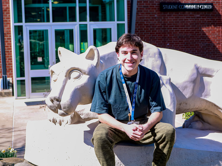 Student smiling by the Greater Allegheny Lion Shrine