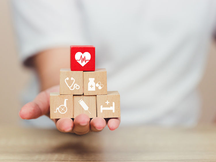 A hand holding building blocks representing different aspects of healthcare