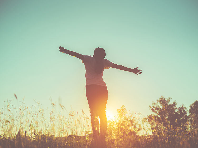 A woman standing in a field posing in the sunset