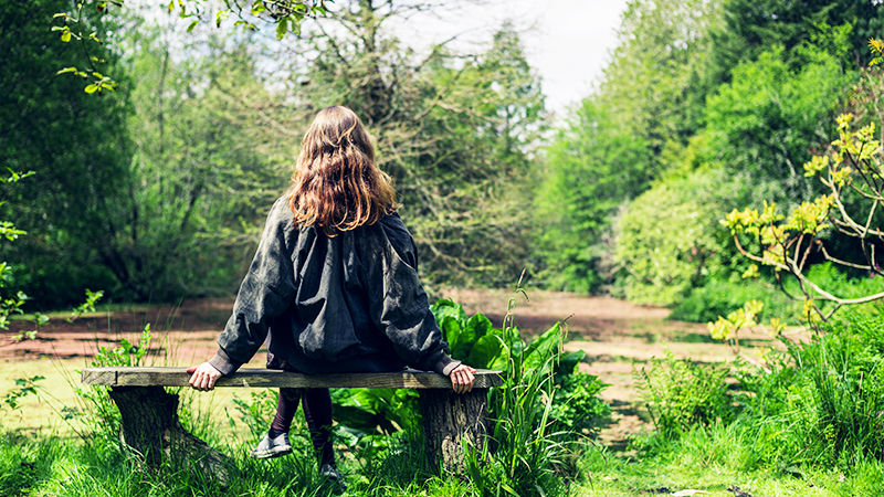 Woman sitting on bench by pond