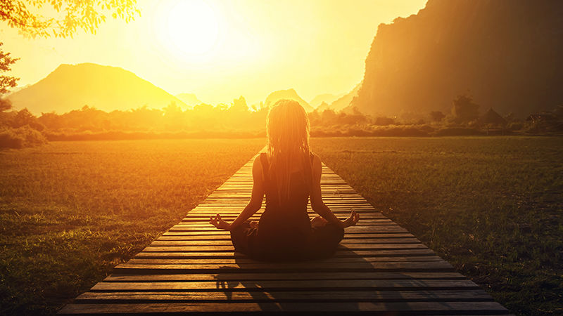 Woman meditating at sunrise