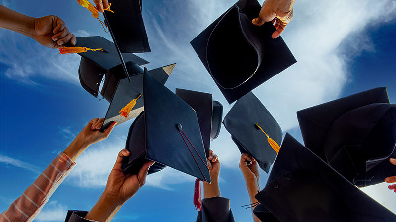 Graduates holding their caps in the air