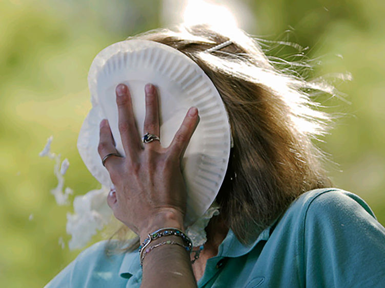 A woman with a plate of whipped cream in her face