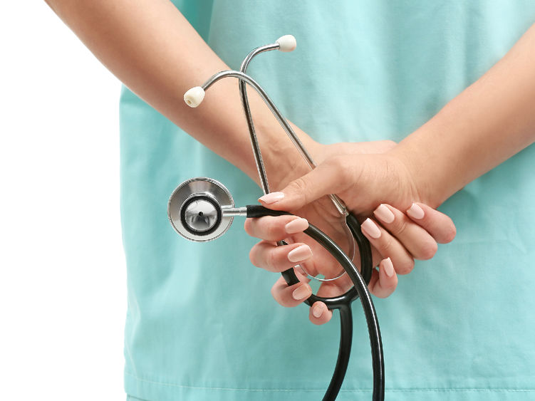 A nurse holding a stethoscope behind her back