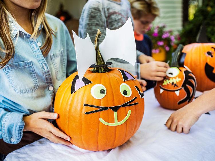 A decorated pumpkin held by a female