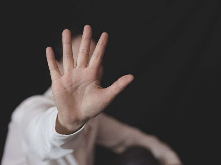 A photo of a woman holding her hand out to stop a sexual assault