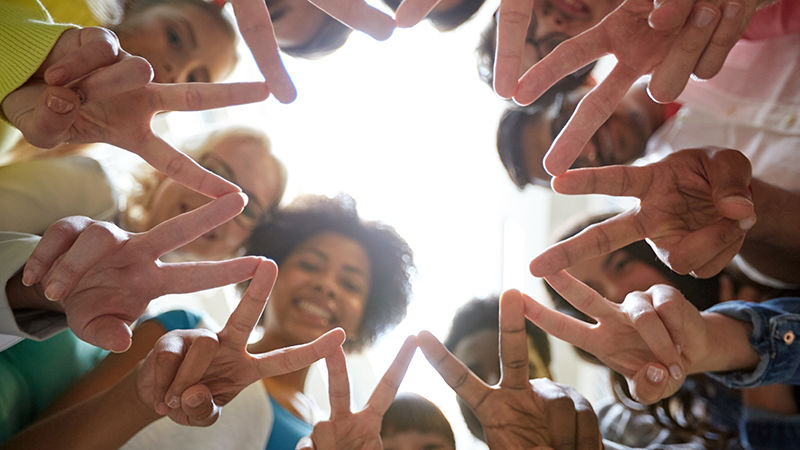 A circle of people giving the peace sign