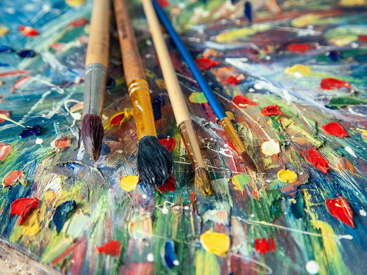 Several paint brushes laying on top of a piece of art