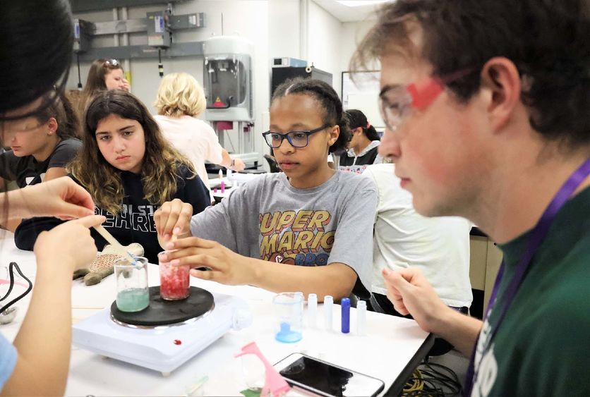 Several youth work with colored fluids in a lab at Penn State Behrend